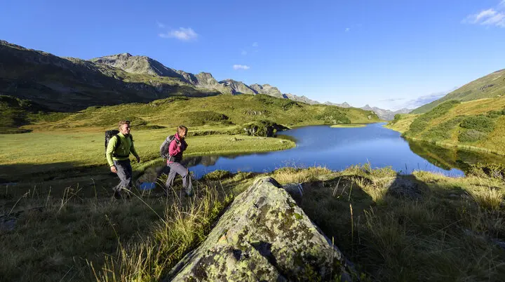 Wanderer im Frühling - im Hintergrund ein Bergsee | © DAV/Wolfgang Ehn